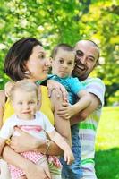 Feliz pareja joven con sus hijos divertirse en el parque foto