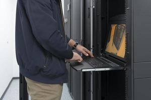 Close up on Data Center Engineer hands Using keyboard on a supercomputer Server Room Specialist Facility with Male System Administrator Working with Data Protection Network for Cyber Security. photo