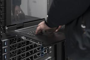 Close up on Data Center Engineer hands Using keyboard on a supercomputer Server Room Specialist Facility with Male System Administrator Working with Data Protection Network for Cyber Security. photo