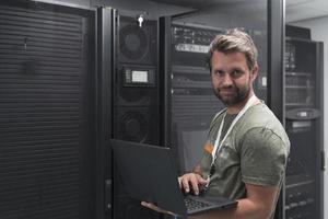 Data Center Engineer Using Laptop Computer Server Room Specialist Facility with Male System Administrator Working with Data Protection Network for Cyber Security or Cryptocurrency Mining Farm. photo