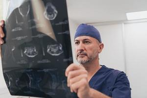 médico ortopedista que examina la imagen de rayos X en el hospital o la clínica foto