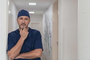 retrato de un médico maduro en un concurrido corredor de hospital moderno. foto