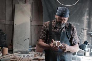 Spoon master in his workshop with wooden products and tools photo