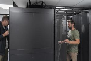 Technicians team updating hardware inspecting system performance in super computer server room or cryptocurrency mining farm. photo