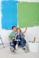 pareja joven feliz relajándose después de pintar en un nuevo hogar foto