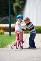 Boy and girl in park learning to ride a bike photo