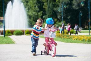 niño y niña en el parque aprendiendo a andar en bicicleta foto