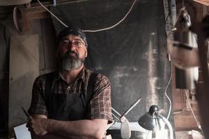 Spoon craft master in his workshop with handmade wooden products and tools photo