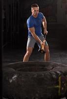 man workout with hammer and tractor tire photo