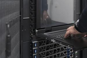 Close up on Data Center Engineer hands Using keyboard on a supercomputer Server Room Specialist Facility with Male System Administrator Working with Data Protection Network for Cyber Security. photo