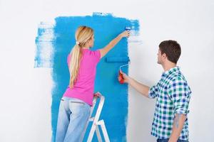 happy couple paint wall at new home photo