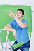 un joven apuesto pinta una pared blanca en color foto