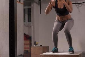 black woman is performing box jumps at gym photo