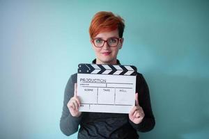 redhead woman holding movie  clapper on cyan background photo