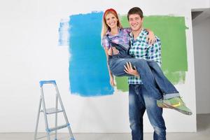 pareja feliz pintando una pared en su nuevo hogar foto