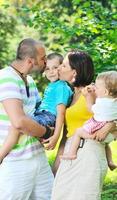 Feliz pareja joven con sus hijos divertirse en el parque foto