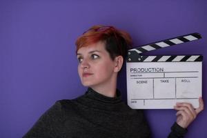 redhead woman holding movie  clapper on purple background photo