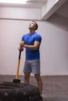 entrenamiento de hombre con martillo y neumático de tractor foto