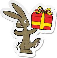 pegatina de un conejo de dibujos animados con regalo de navidad vector