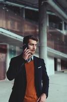 businessman architect using a smartphone while overseeing the construction site photo