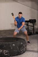 man workout with hammer and tractor tire photo