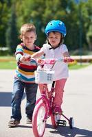 Boy and girl in park learning to ride a bike photo