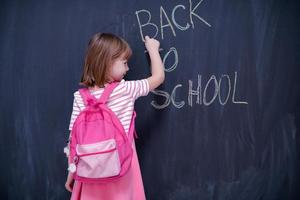 school girl child with backpack writing  chalkboard photo