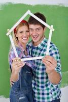 pareja feliz pintando una pared en su nuevo hogar foto