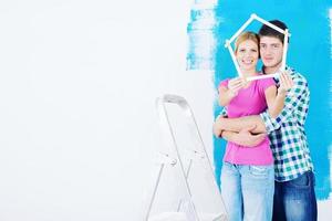 pareja feliz pintando una pared en su nuevo hogar foto