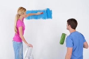 pareja feliz pintando una pared en su nuevo hogar foto