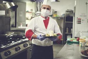 chef cook wearing face protective medical mask for protection from coronavirus photo