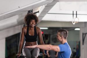 mujer negra haciendo ejercicio de barras paralelas con entrenador foto