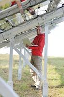 engineer using laptop at solar panels plant field photo