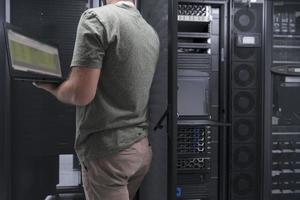 Data Center Engineer Using Laptop Computer Server Room Specialist Facility with Male System Administrator Working with Data Protection Network for Cyber Security or Cryptocurrency Mining Farm. photo