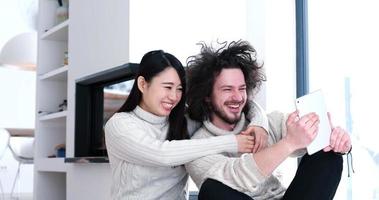 young multiethnic couple using a tablet on the floor photo