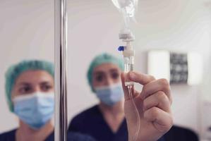 General practitioner holding intravenous drip infusion. Doctor handling IV fluid drip with copy space on white background. Nurse performing Intravenous therapy. photo