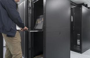 Close up on Data Center Engineer hands Using keyboard on a supercomputer Server Room Specialist Facility with Male System Administrator Working with Data Protection Network for Cyber Security. photo