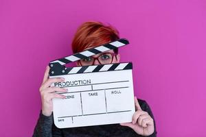 woman holding movie clapper isolated on pink background photo