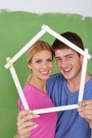 pareja feliz pintando una pared en su nuevo hogar foto