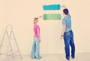 pareja feliz pintando una pared en su nuevo hogar foto