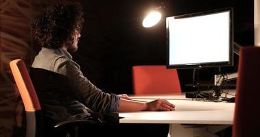 hombre trabajando en una computadora en una oficina oscura foto