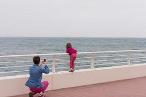 madre y niña linda en el paseo marítimo junto al mar foto