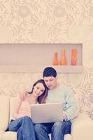 pareja joven trabajando en una laptop en casa foto