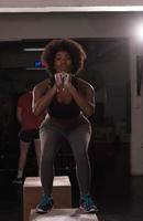 atleta femenina negra está realizando saltos de caja en el gimnasio foto