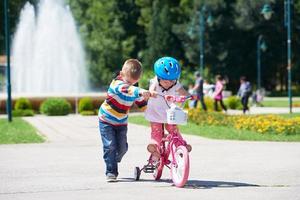 Boy and girl in park learning to ride a bike photo