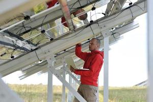 engineer using laptop at solar panels plant field photo