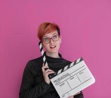 mujer pelirroja sosteniendo la chapaleta de la película sobre fondo rosa foto