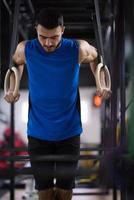 hombre haciendo pull ups con anillos de gimnasia foto