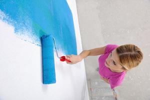 mujer sonriente feliz pintando el interior de la casa foto