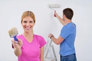 pareja feliz pintando una pared en su nuevo hogar foto